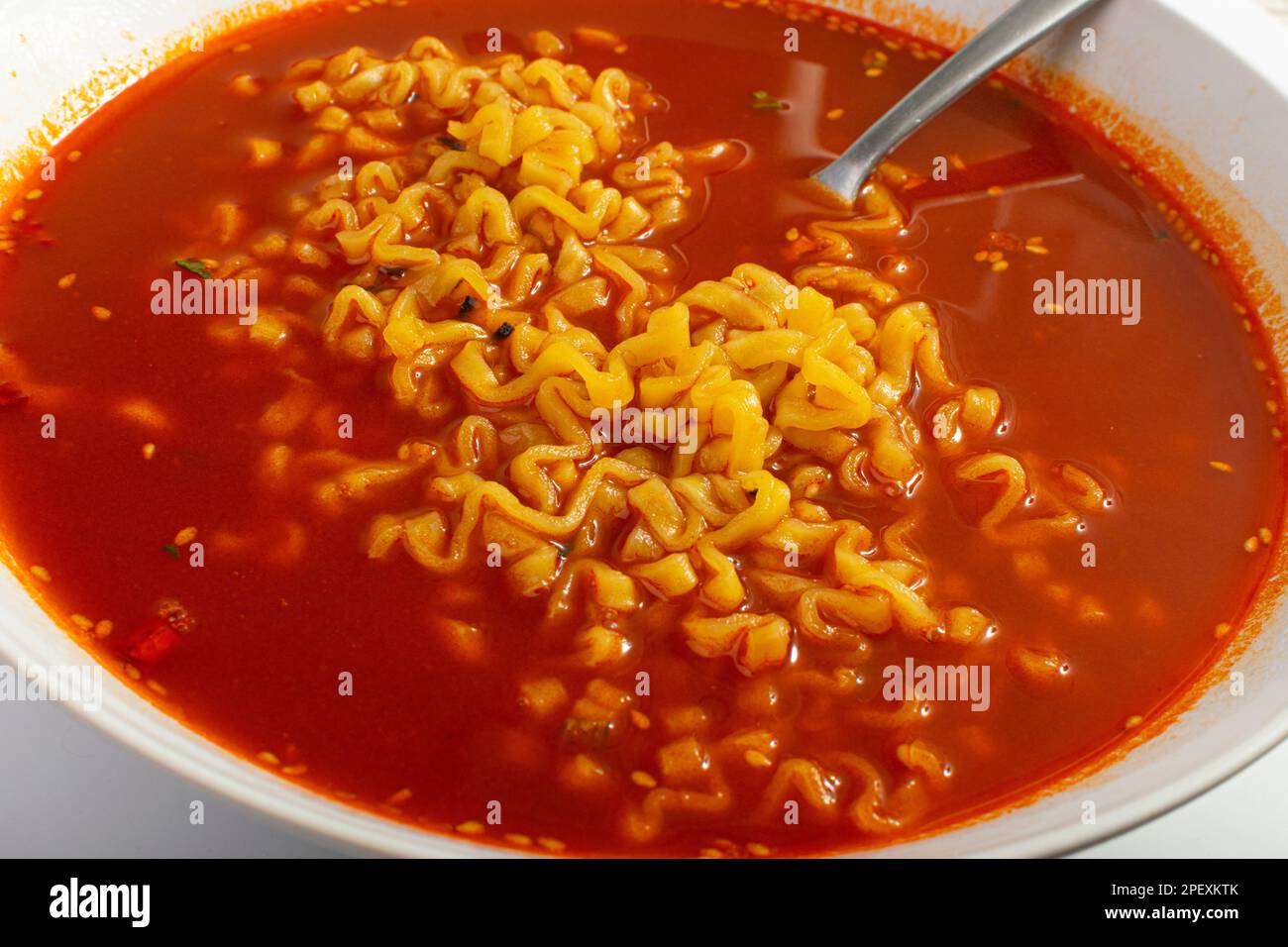 Rote scharfe Nudelsuppe in weißer Schüssel, Nahaufnahme mit Hot Chili-Pfeffer-Ramen-Struktur, scharfe koreanische Speisen Stockfoto