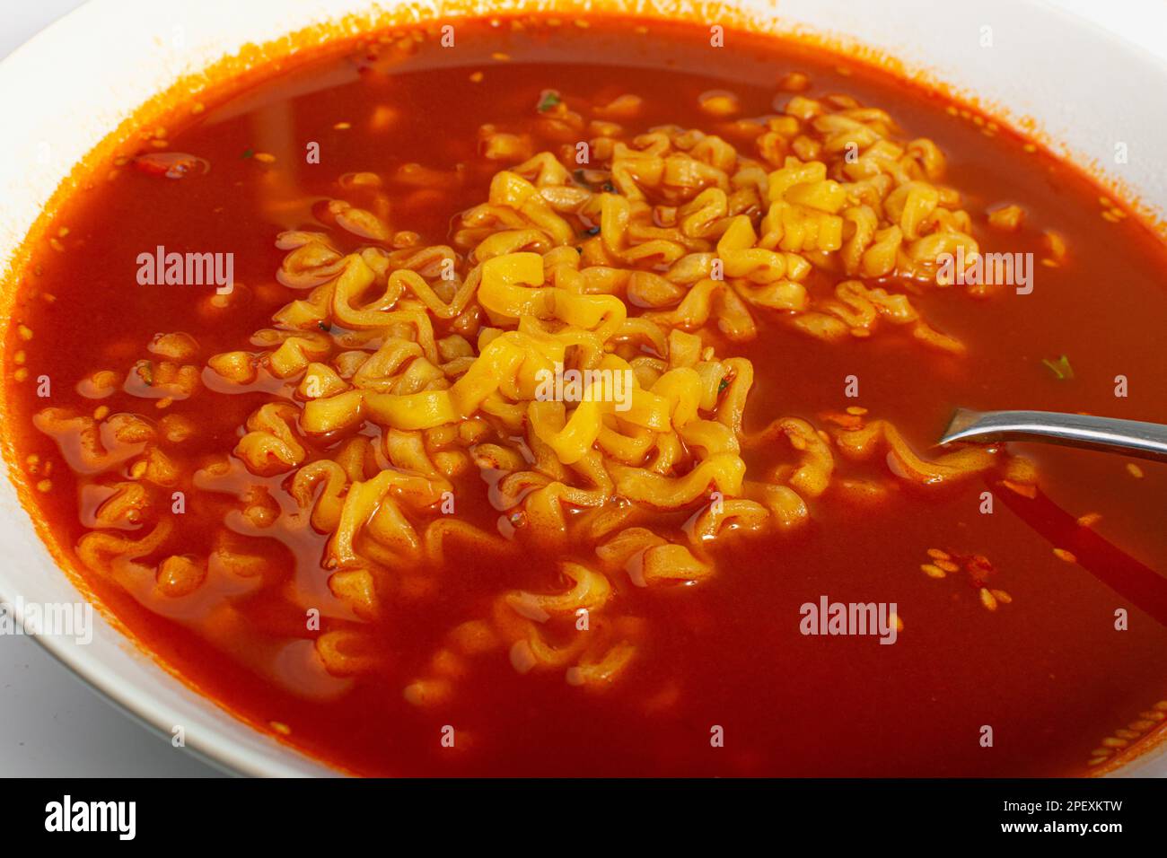 Rote scharfe Nudelsuppe in weißer Schüssel, Nahaufnahme mit Hot Chili-Pfeffer-Ramen-Struktur, scharfe koreanische Speisen Stockfoto