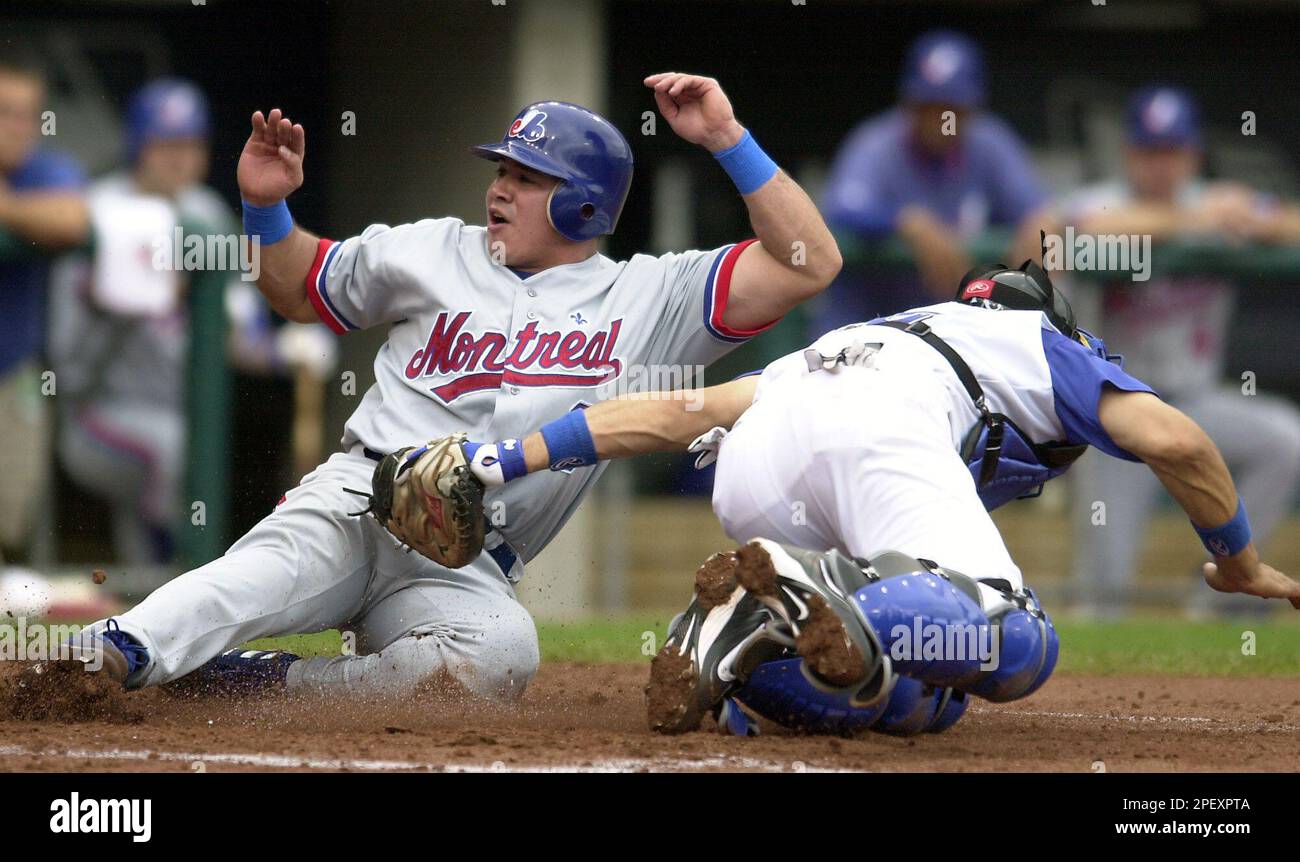 Montreal Expos' Einar Diaz, left, slides safely into home past the tag of Kansas City Royals catcher Benito Santiago as he scores from third on a fielder's choice in the first inning of the first game of a doubleheader Thursday, June 10, 2004, in Kansas City, Mo. Jose Vidro grounded the ball to shortstop Angel Berroa who was late with the throw to home. (AP Photo/Ed Zurga) Stockfoto