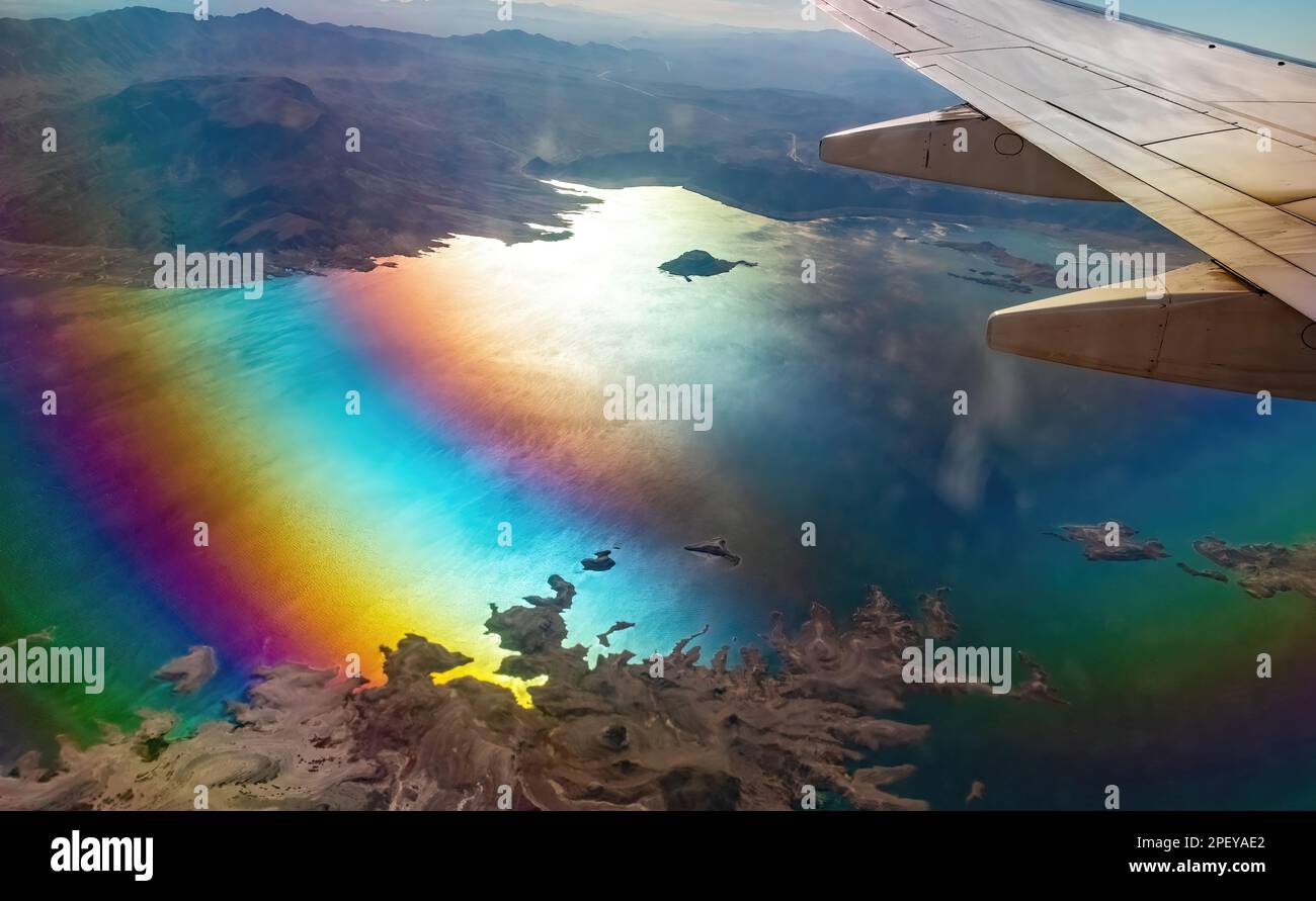 Fliegen Sie hoch in den Wolken über die Landschaft der Berge, Hügel und Gewässer von Colorado, USA, mit einer wunderschönen Regenbogenreflexion. Stockfoto