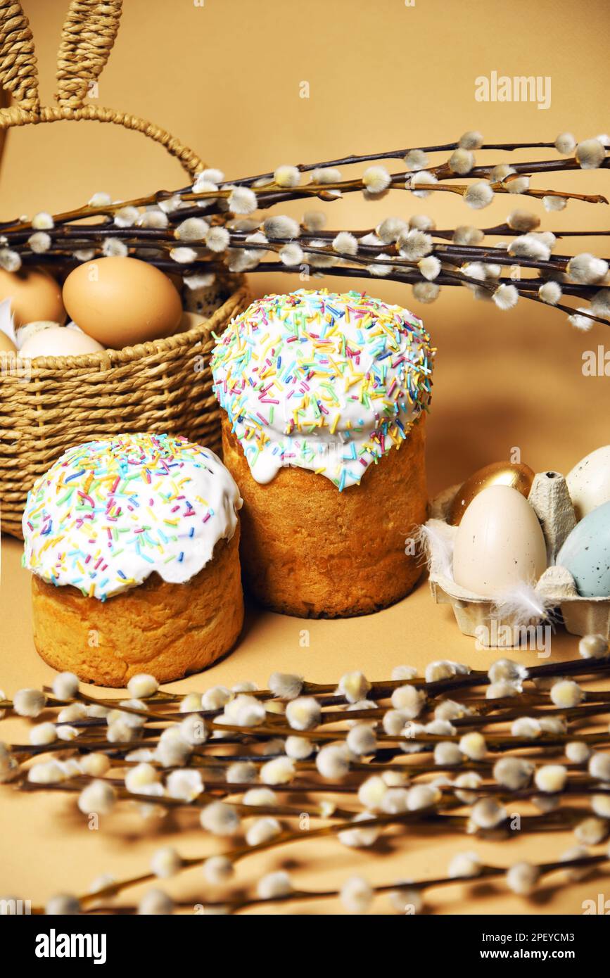 Osterferien, Weide, bunte bemalte Eier in einem Tablett, ein Korb mit Osterkuchen auf nacktem Hintergrund, warm. Religion und Traditionen Stockfoto