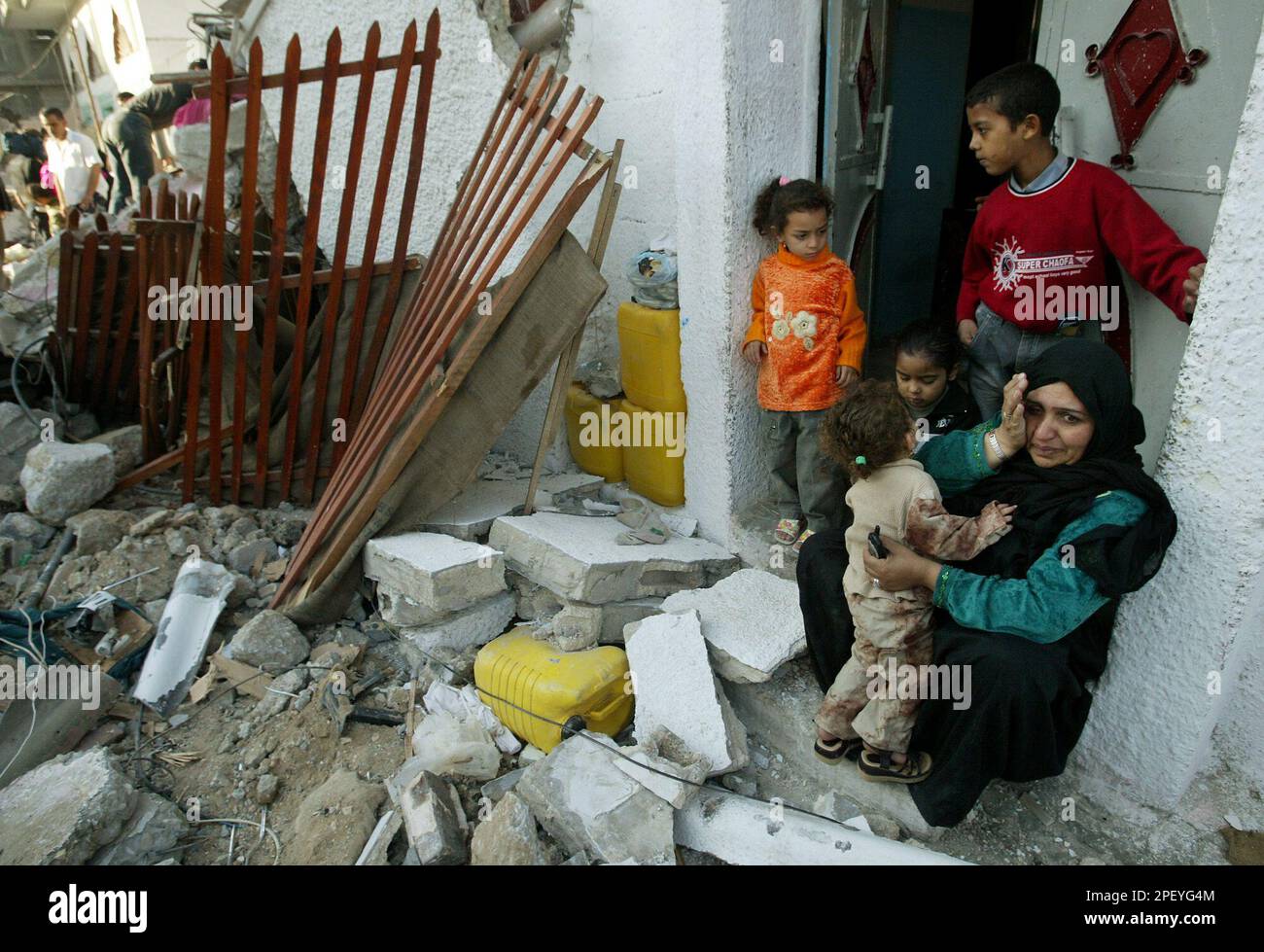 A Palestinian woman weeps as she sits in her front door with her ...