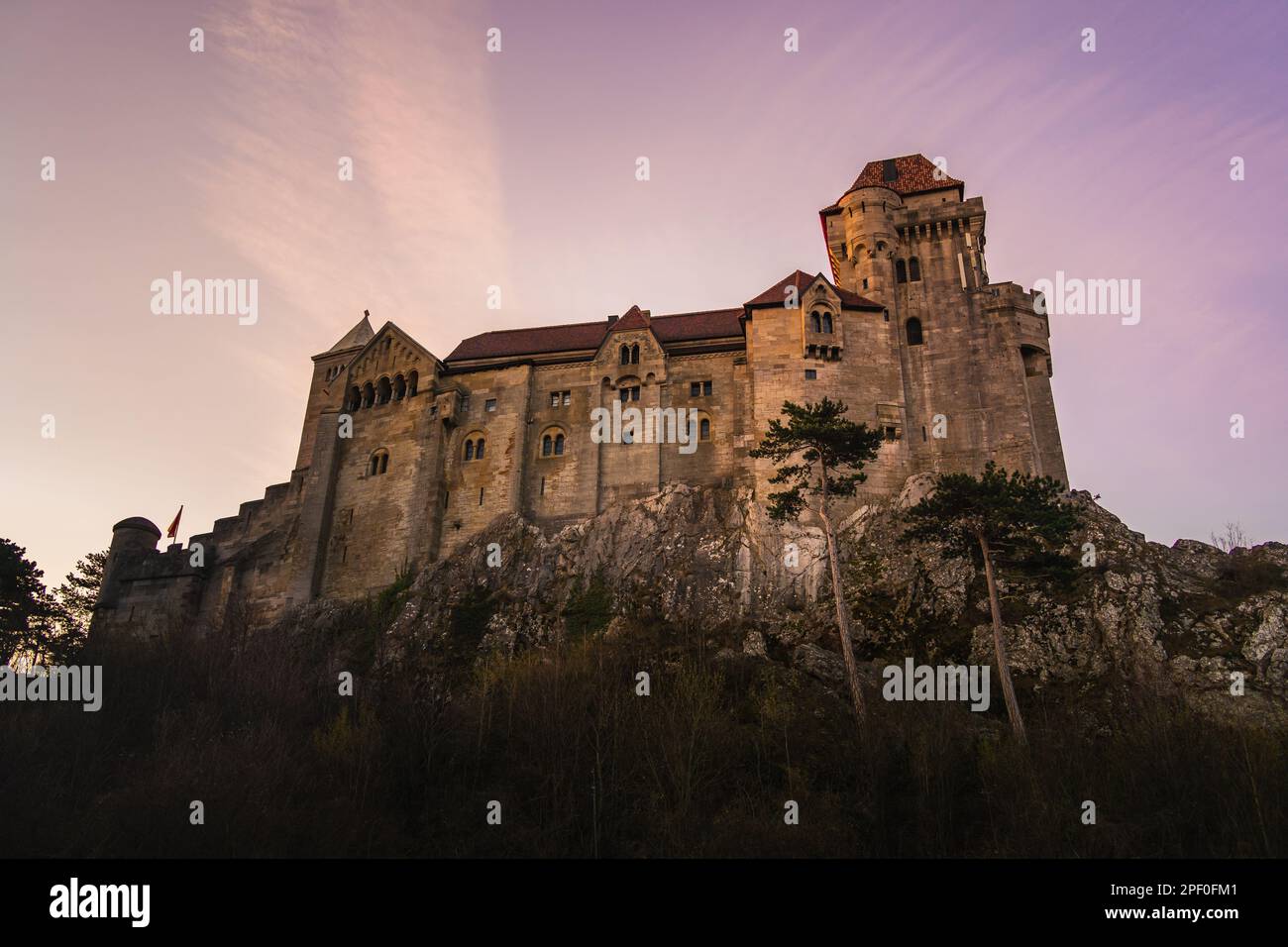 Dieses majestätische, burgähnliche Gebäude befindet sich auf einer felsigen Klippe, umgeben von üppig grünen Bäumen Stockfoto