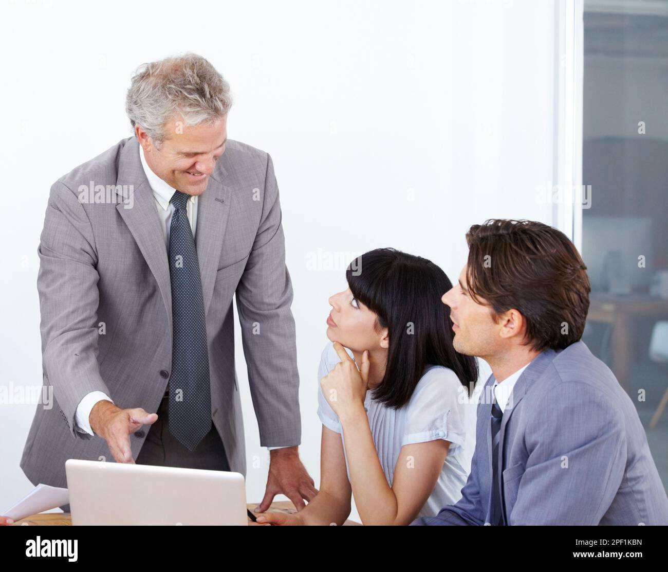 Er gab ihnen seinen angesehenen Rat. Ein Geschäftsführer, der seine beiden jüngeren Kollegen bei einem Meeting berät. Stockfoto