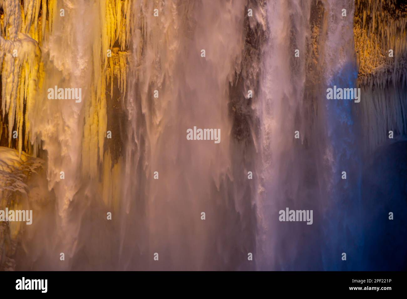 Details von Stalagmiten und Wasser, das aus dem Skógafoss-Wasserfall in Island fällt, erleuchtet durch das abendliche Sonnenlicht und schafft eine märchenhafte Atmosphäre wie Stockfoto