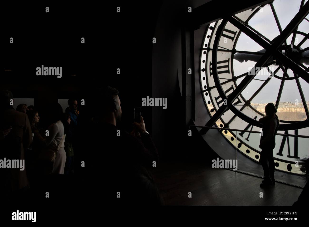 Eine unbekannte Frau im Schatten, die von ihrem Begleiter auf der Uhr des Orsay Museums fotografiert wird Stockfoto