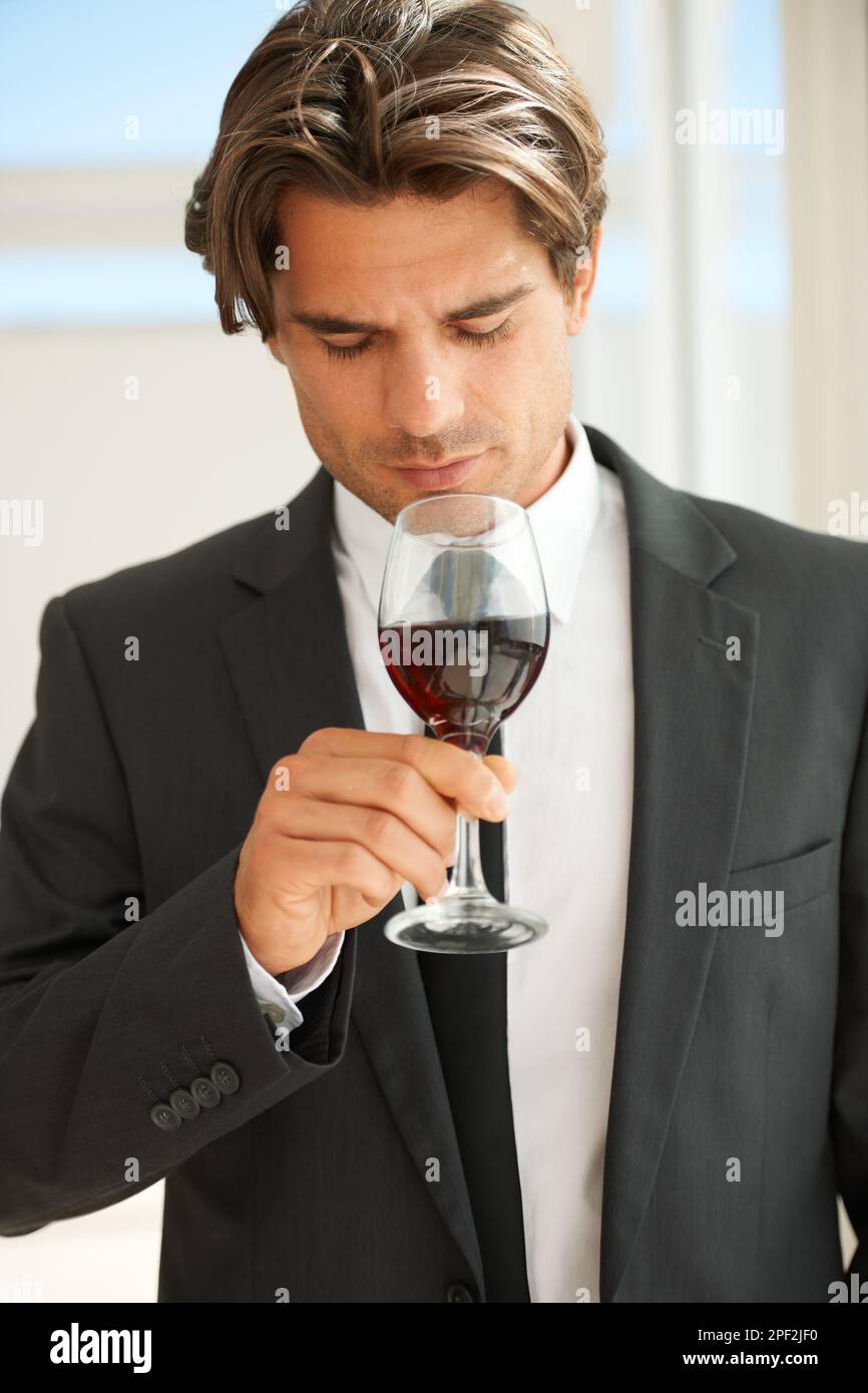 Ich überprüfe die Nase des Weins. Ein hübscher Weinkenner, der ein Glas Rotwein genießt. Stockfoto