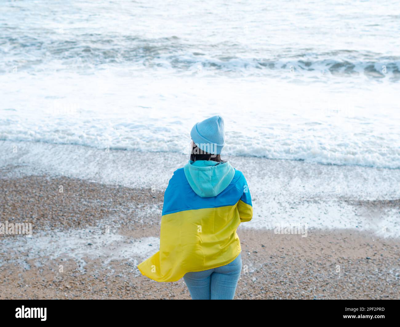 Braune Frau in blauem Hoodie und blauem Hut mit ukrainischer Nationalflagge, patriotisches Konzept Stockfoto