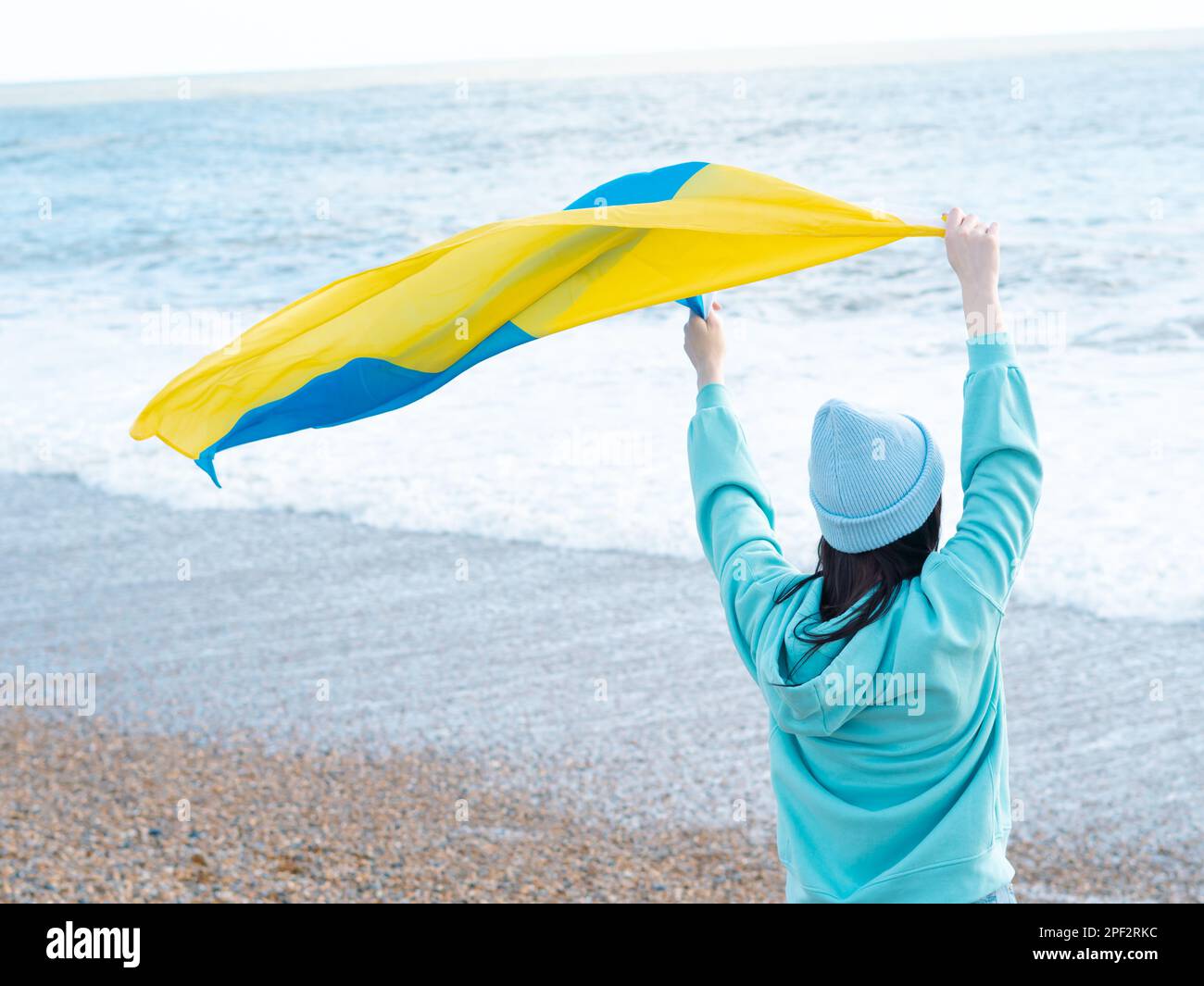Braune Frau in blauem Hoodie und blauem Hut mit ukrainischer Nationalflagge, patriotisches Konzept Stockfoto