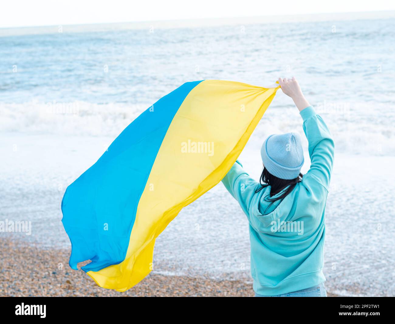 Braune Frau in blauem Hoodie und blauem Hut mit ukrainischer Nationalflagge, patriotisches Konzept Stockfoto