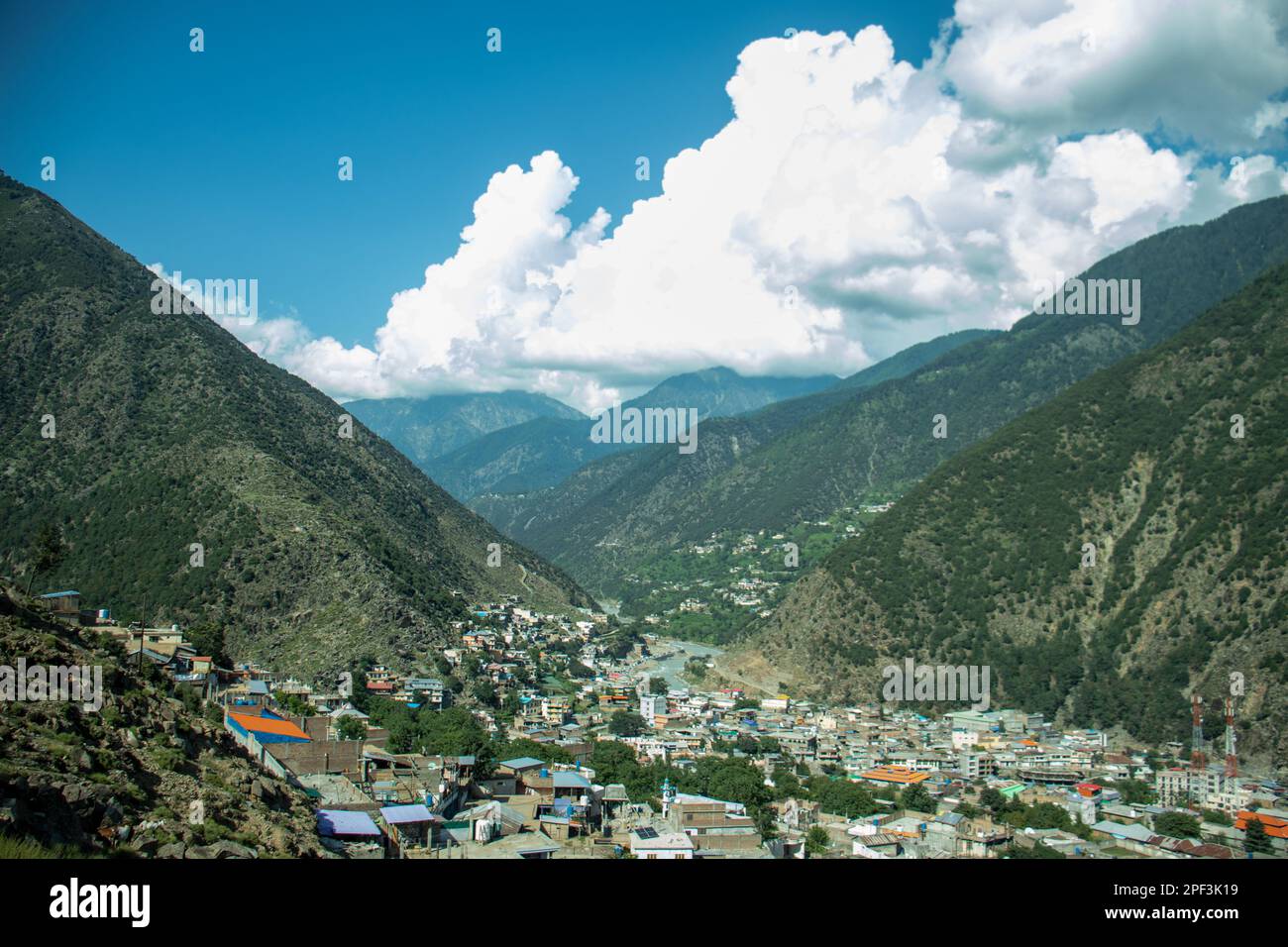 Mountain Valley Serenity: Häuser eingebettet zwischen Majestic Peaks und aufragenden Wolken Stockfoto