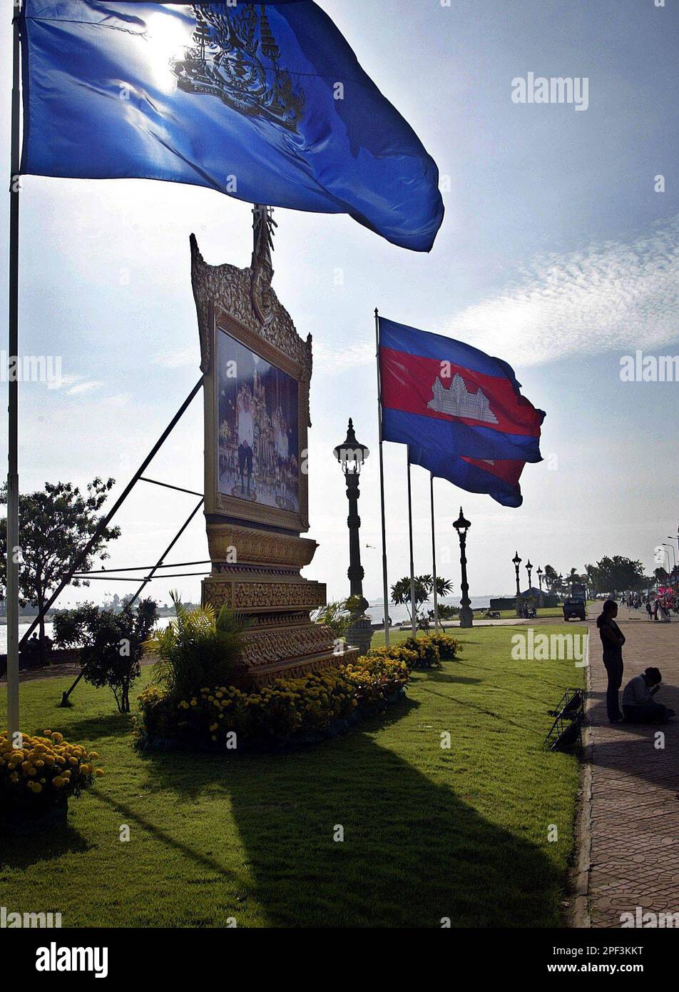 Combodian First Ruler Cambodian national and Royal flags flutter next to a portrait of King ...