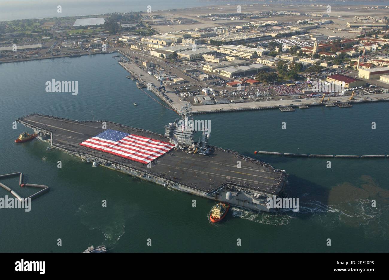 The US Navy aircraft carrier USS Nimitz is nursed to its' berth with tugboats at North Island Naval Air Station after an eight month deployment to the conflict in Iraq Wednesday, Nov. 5, 2003. The carrier was the last to arrive there and the last to return home. The nuclear-powered aircraft carrier led a strike group that included the USS Princeton guided missile cruiser and the USS Bridge combat support ship. It joined five other carrier battle groups in the Persian Gulf to form an unprecedented floating air force within striking distance of Iraq. (AP Photo/San Diego Union-Triibune Photo, Joh Stockfoto