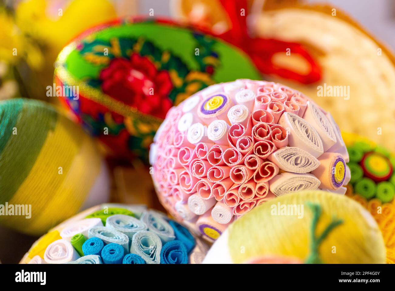 Farbenfrohe traditionelle Ostereier mit Blumenverzierungen, Origami-Dekorationen und Kreppwolle, Nahaufnahme. Stockfoto