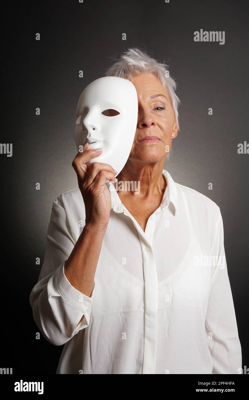 Ernsthafte Suche reife Frau zeigt wahres Gesicht hinter der Maske Stockfoto