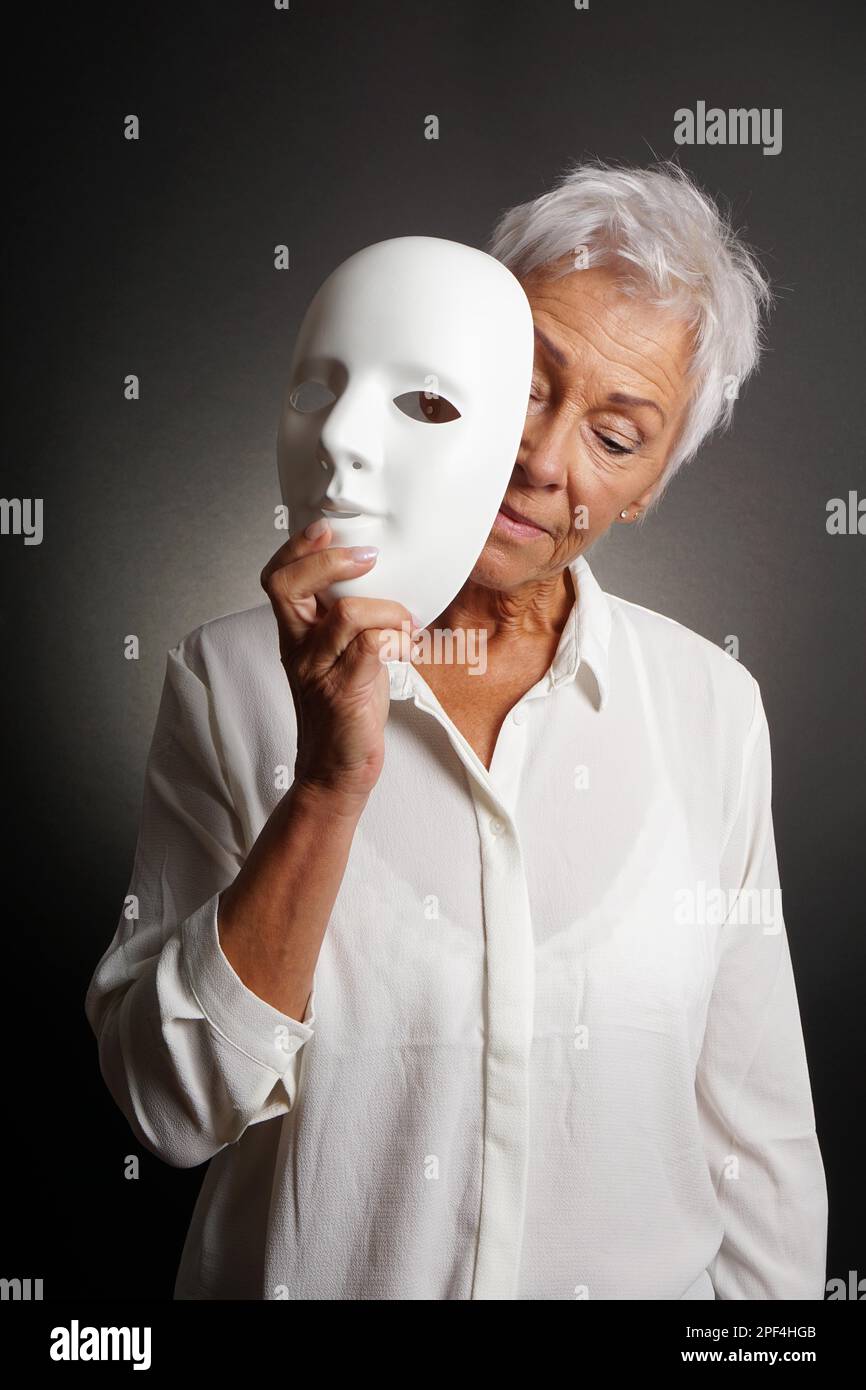 Reife Frau mit traurigem Gesicht hinter der Maske. Depressionskonzept Stockfoto