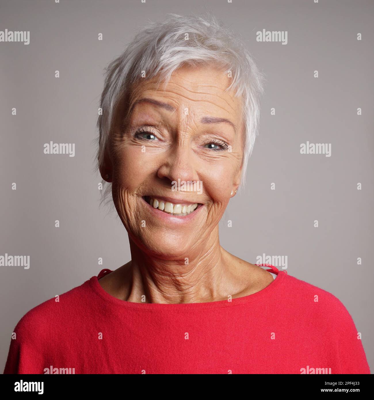 Gerne ältere Frau in ihrem 60s mit trendigen kurzen weißen Haar lachend Stockfoto