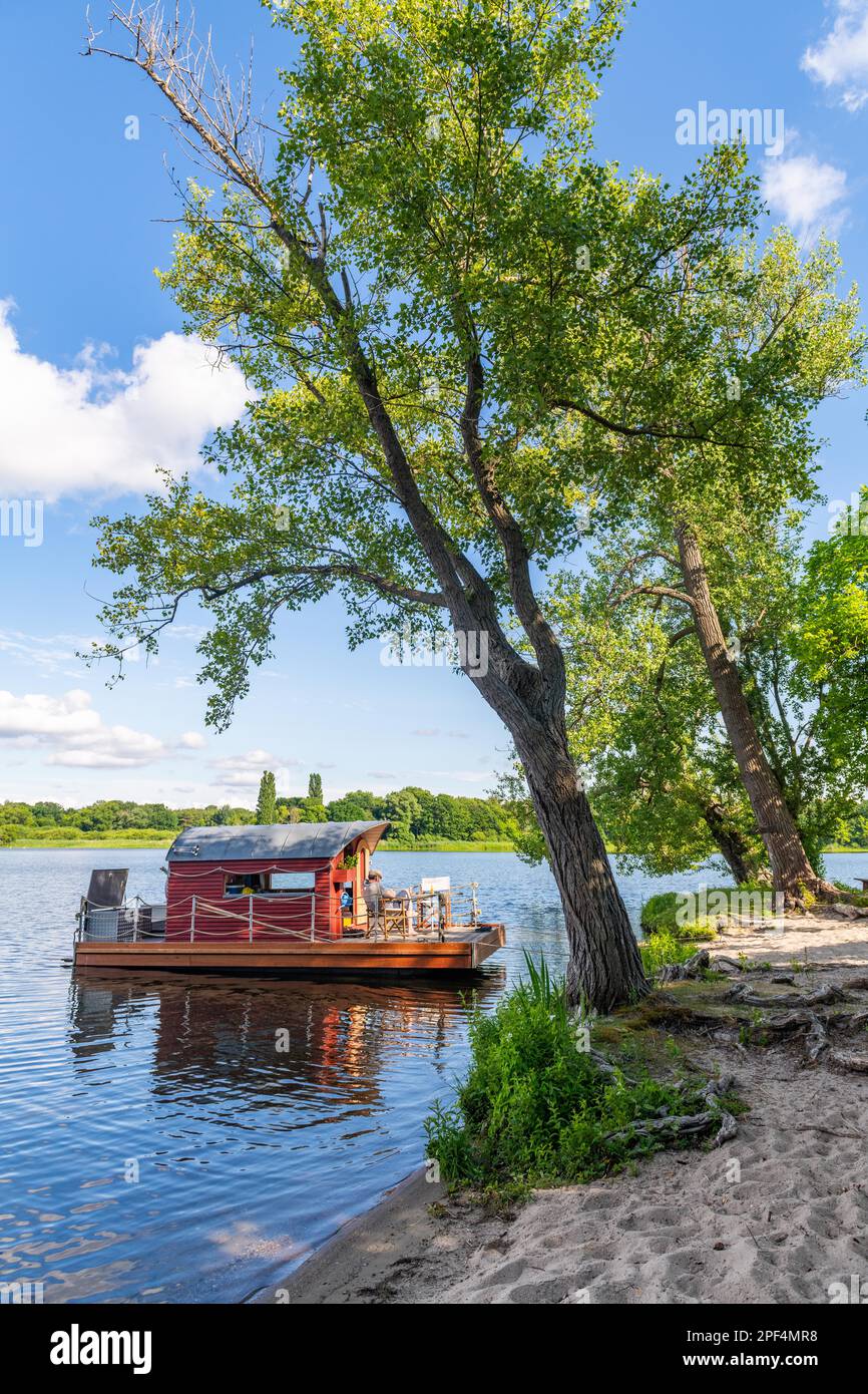 Mann sitzt auf einem Hausboot, Hausfloß, vor der Insel Kiehnwerder, Breitlingsee, Brandenburg an der Havel, Havelland, Brandenburg, Deutschland Stockfoto