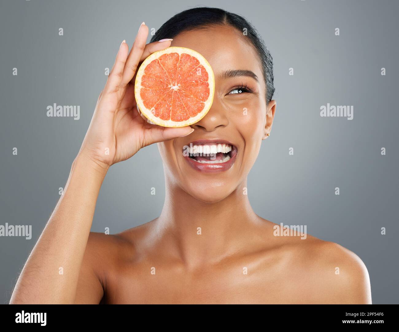 Grapefruit für den Sieg. Eine schöne junge Frau, die mit einer halbierten Grapefruit posiert. Stockfoto