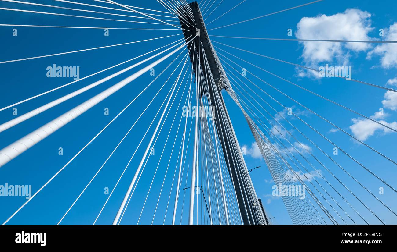 Moderner Brückenpylon vor blauem Himmel. Detail der mehrspaltigen Kabelbrücke. Lineare perspektivische Ansicht einer weissen Kabelaufhängung Alex Stockfoto