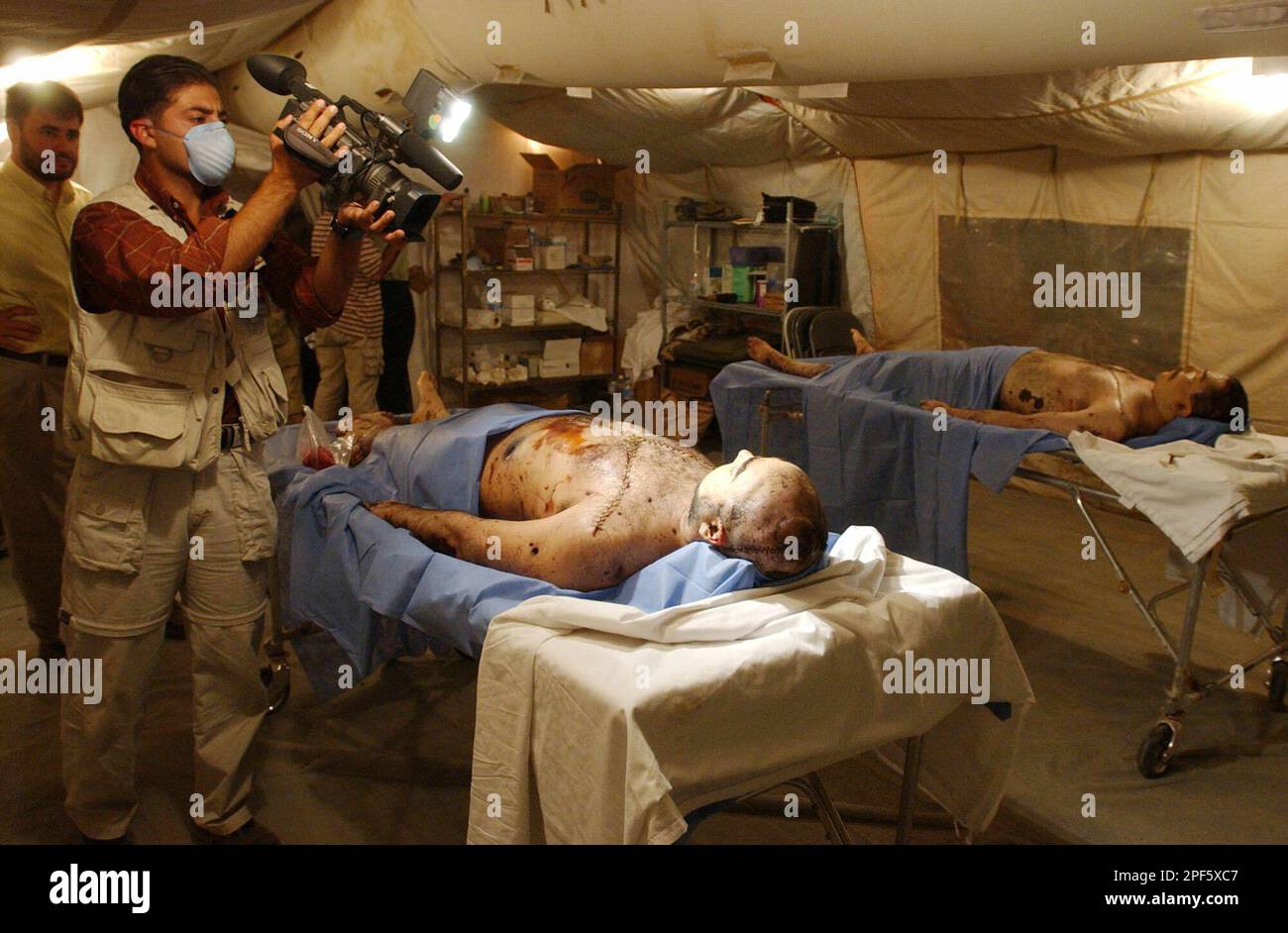A cameraman films the bodies of former Iraqi President Saddam Hussein's two sons Odai, left, and Qusai, in the US Air Force morgue at Baghdad airport, Friday July 25, 2003. (AP Photo/Stan Honda, pool) Stockfoto