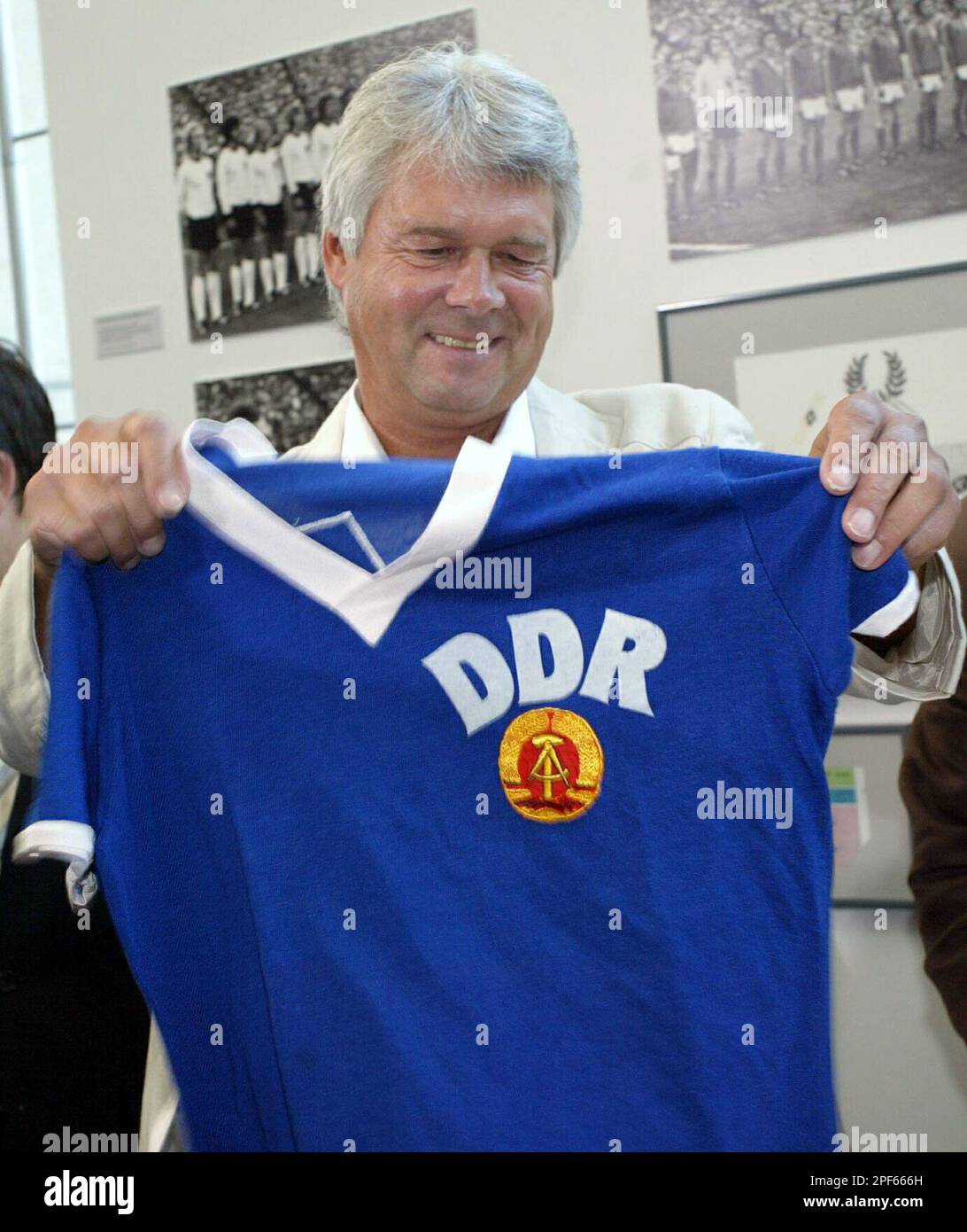 Der fruehere Fussball-Nationalspieler der damaligen DDR, Juergen Sparwasser, zeigt am Donnerstag, 10. Juli 2003, im Haus der Geschichte in Bonn das Trikot, in dem er bei der Fussballweltmeisterschaft 1974 in Hamburg das 1-0 Siegtor gegen die Bundesrepublik Deutschland schoss. In der Kabine tauschte er das Trikot dann mit Paul Breitner. Ein Krefelder Kaufmann ersteigerte es zugunsten der Oder-Flutopfer. Jetzt wurde des dem Museum uebergeben. (AP Photo/Hermann J. Knippertz) Stockfoto