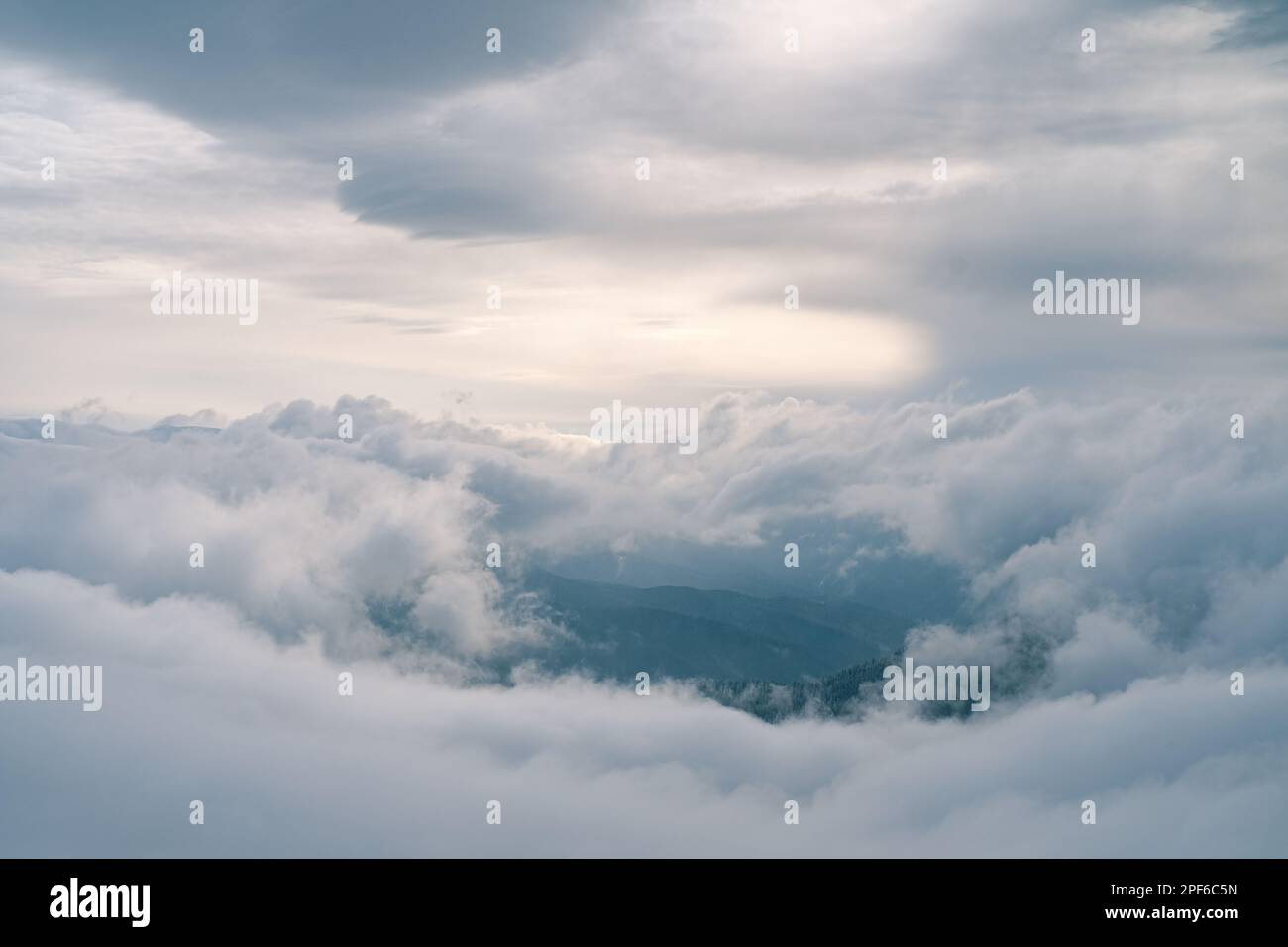 Wolken am Himmel über den Winterbergen, die bei Sonnenuntergang mit Schnee bedeckt sind Stockfoto