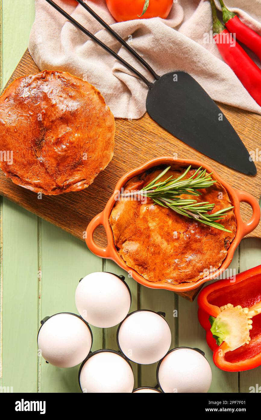 Zusammensetzung mit köstlichen Fleischpasteten und Zutaten auf einem grünen Holztisch Stockfoto