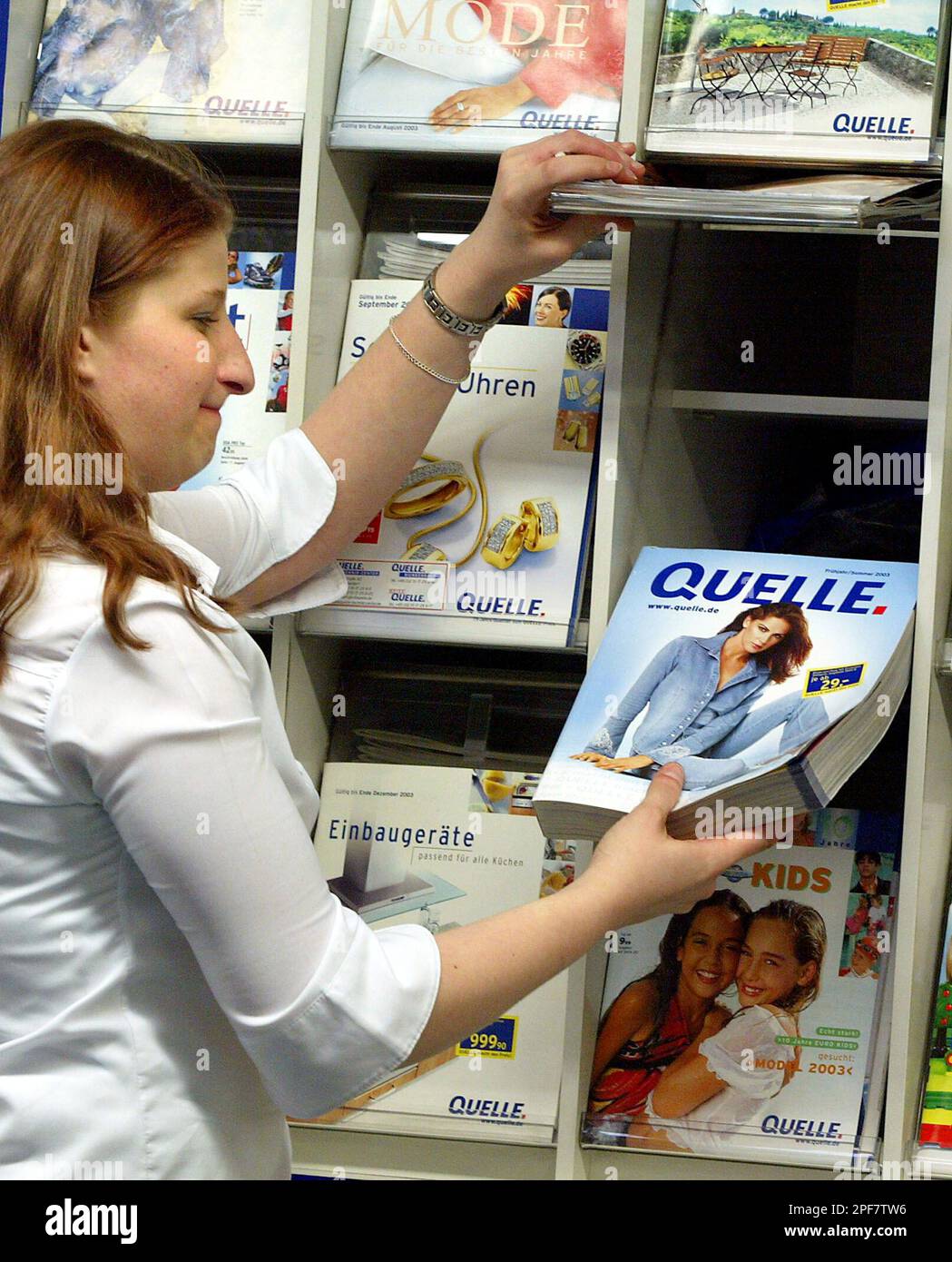 Eine Frau schaut in einen QuelleKatalog in einer QuelleFiliale in