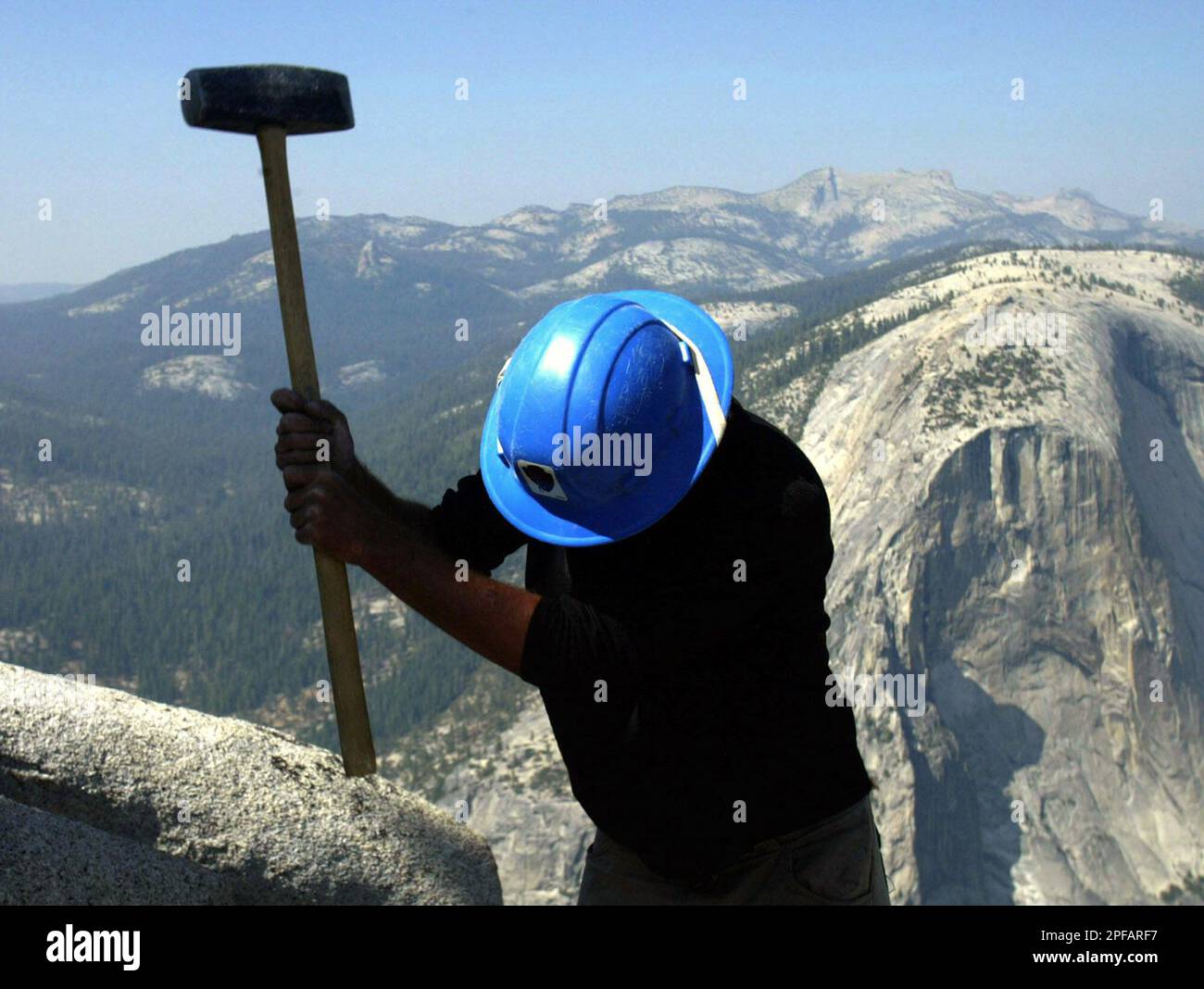 Greg Torres uses a sledge hammer to break up the granite rock during