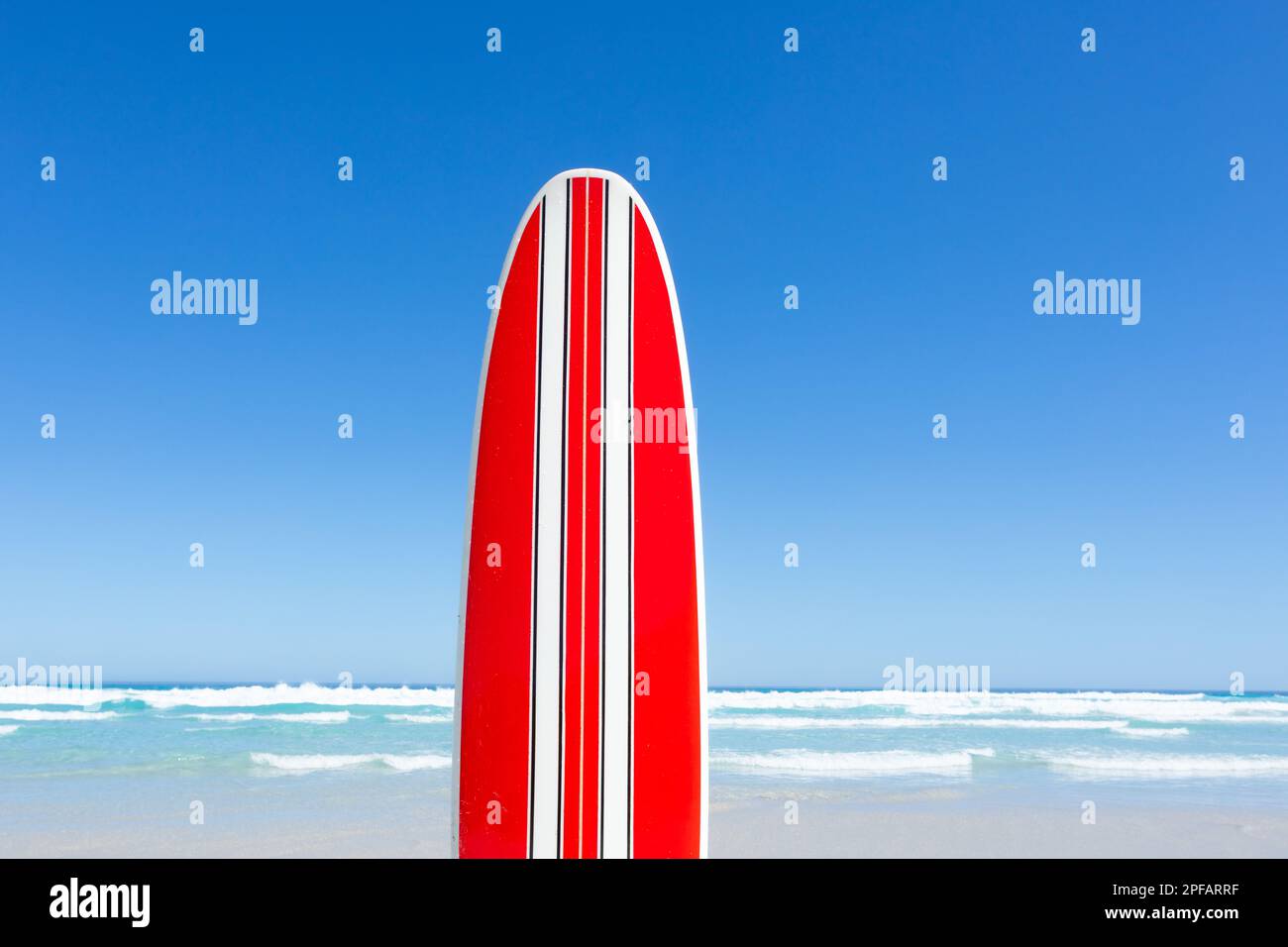 Rot-weiß gestreiftes Surfbrett im Retro-Look. Blauer Himmel und ein Sommertag am Strand. Stockfoto