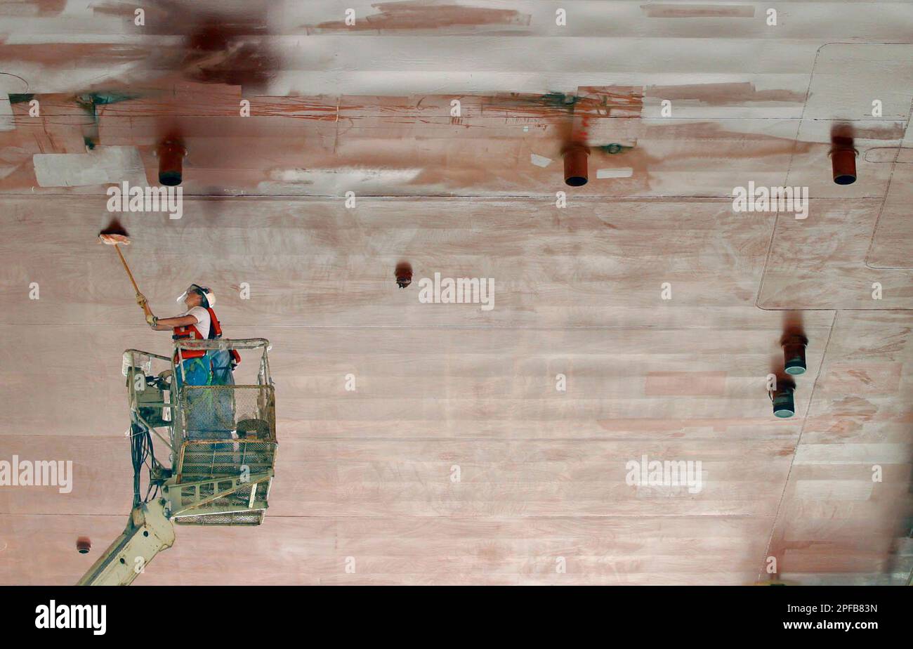 A worker wipes down the bottom deck of an oil rig under construction ...