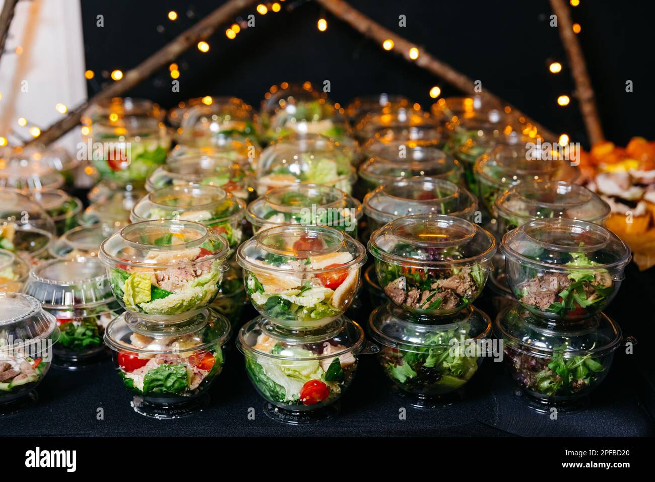 Viele Portionen verschiedener Salate mit Fleisch und Gemüse in Plastiktellern mit Deckeln. Сatering Portionen Salate auf dem Tisch servieren. Büfett Stockfoto