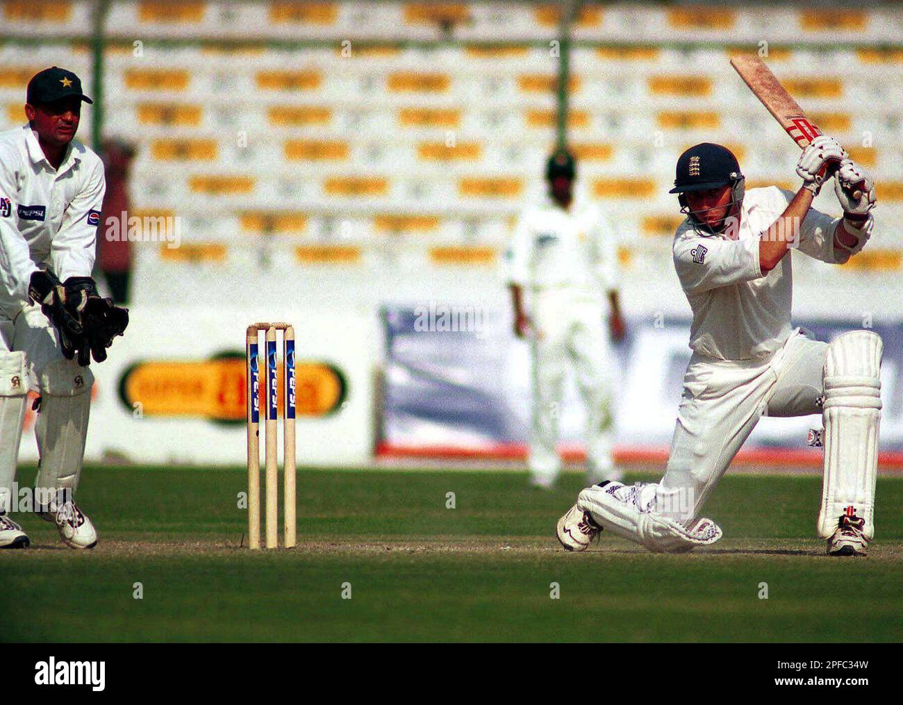 England opener Michael Atherton, right, plays a cover drive as Pakistan wicketkeeper Moin Khan looks on during the third day of the third cricket test, Saturday, Dec. 9, 2000 at National Stadium in Karachi. (AP Photo/Zia Mazhar) Stockfoto
