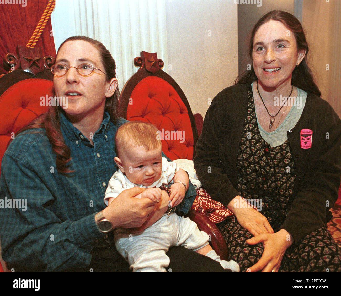 Stacey Jolles, left, and Nina Beck, with their son Seth, 4 months, talk to reporters after the Vermont House approved a bill that would give gays and lesbians the same rights and benefits as married, heterosexual couples at the Statehouse in Montpelier, Vt, Thursday, March 16, 2000. Jolles and Beck were two of the original six plaintiffs that brought suit against their town clerks when they were denied a marriage license because they were gay. (AP Photo/Craig Line) Stockfoto