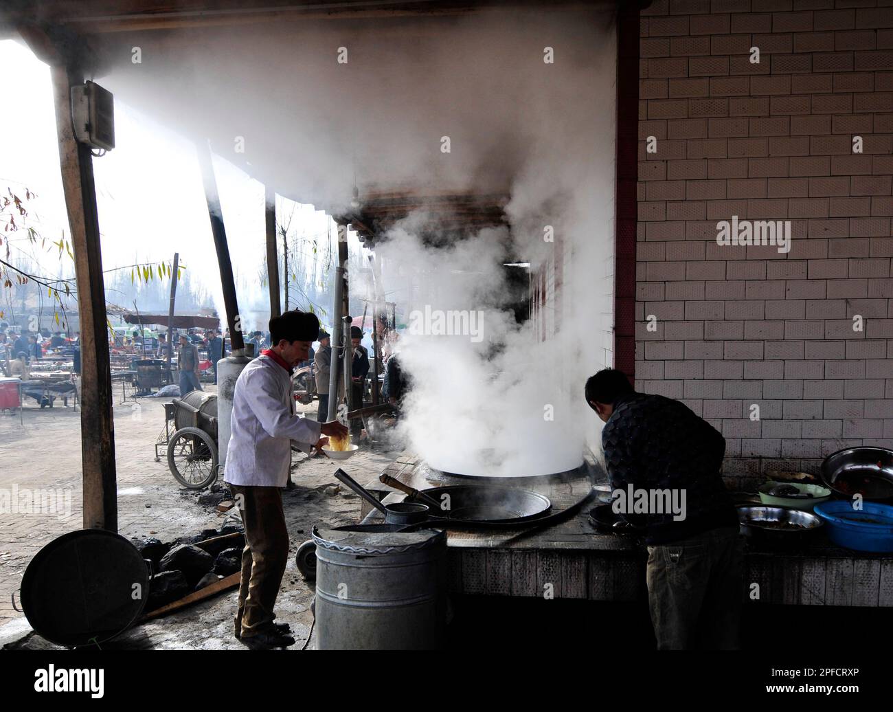 Ein kleines Straßenrestaurant, das Lagman-Nudeln und Reis mit Teigtaschen auf einem wöchentlichen Viehmarkt in den Außenbezirken von Kashgar, Xinjiang, China, serviert. Stockfoto