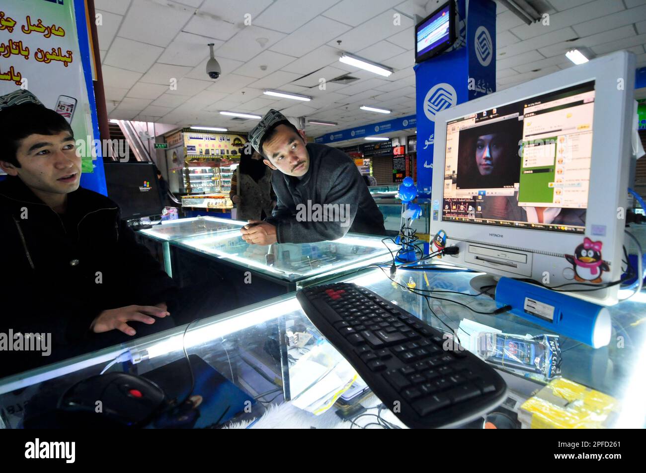 Uiguren-Männer, die sich einen Film auf einem Computer in einem Computer-/elektronischen Einkaufszentrum in Kashgar, China, anschauen. Stockfoto
