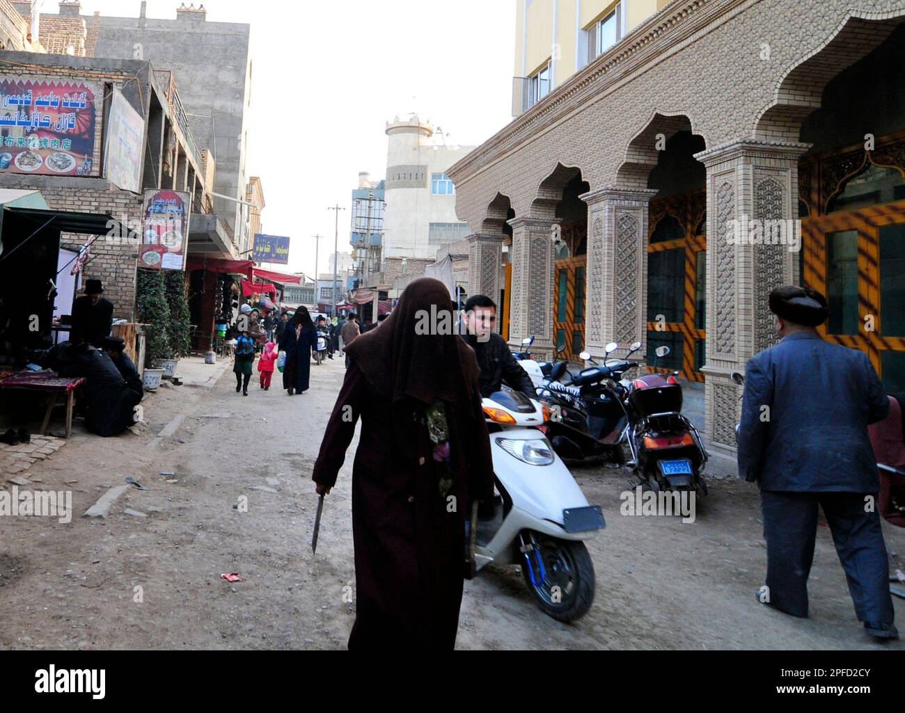 Verschleierte uigurische Frau, die in der Altstadt von Kashgar, Xinjiang, China, spaziert. Stockfoto