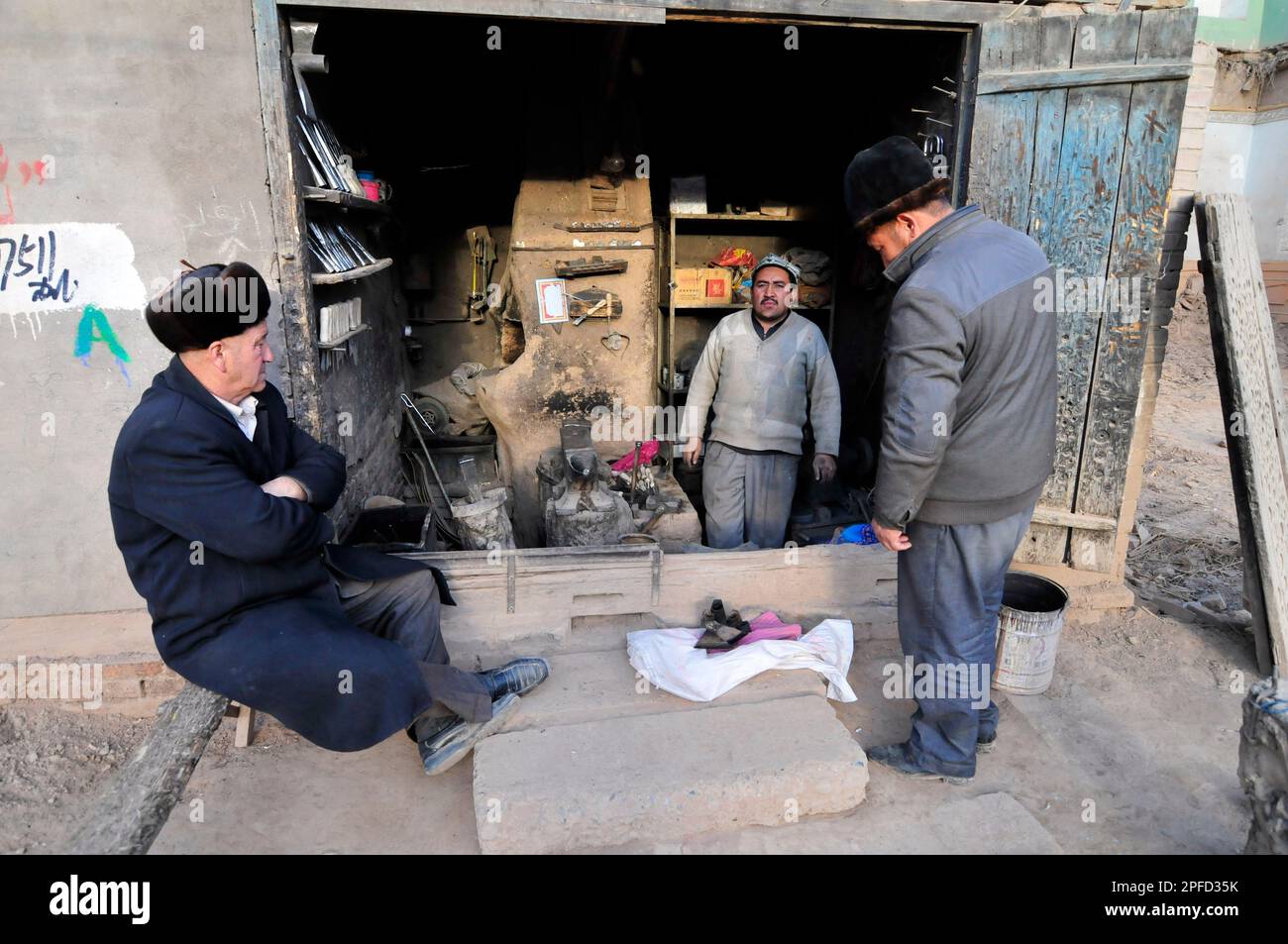 Uiguren stehen vor einer Werkstatt in der Altstadt von Kashgar, Xinjiang, China. Stockfoto