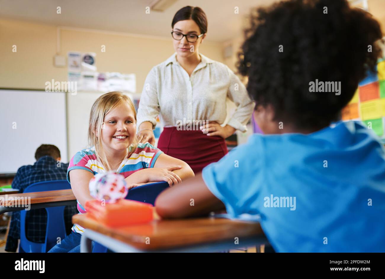 Bitte nicht in meiner Klasse reden. Eine junge, attraktive Lehrerin, die die Kinder in ihrem Klassenzimmer während eines Unterrichts diszipliniert. Stockfoto