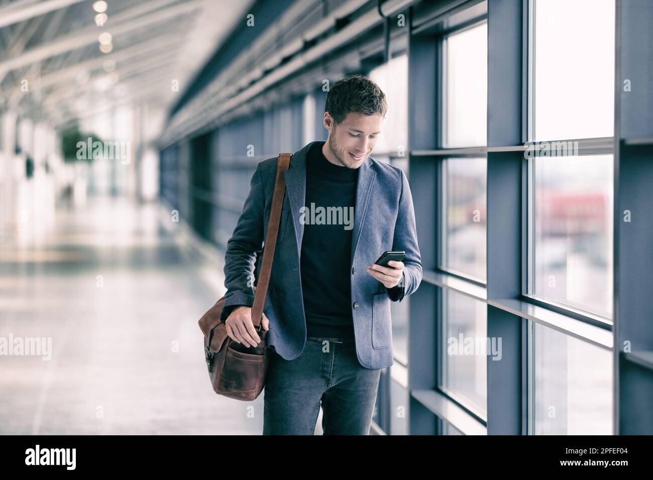 Handy-Geschäftsmann, der mit Kuriertasche auf dem Flughafen läuft und SMS-Nachrichten per Handy über die Smartphone-App schreibt – Geschäftsleute pendeln Stockfoto