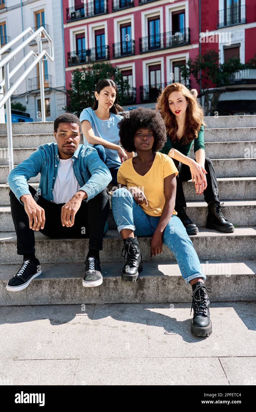 Multikulturelle Gruppe von Freunden, die auf der urbanen Treppe sitzen Stockfoto