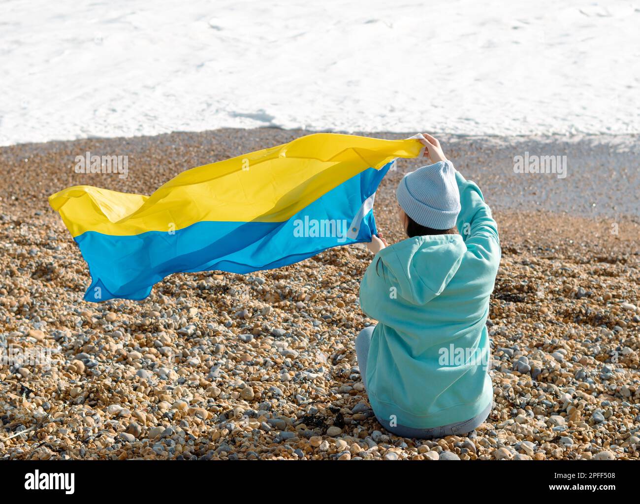 Braune Frau in blauem Hoodie und blauem Hut mit ukrainischer Nationalflagge, patriotisches Konzept Stockfoto