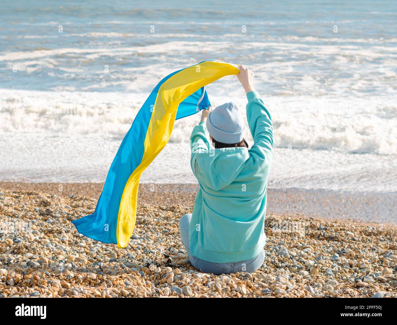 Braune Frau in blauem Hoodie und blauem Hut mit ukrainischer Nationalflagge, patriotisches Konzept Stockfoto
