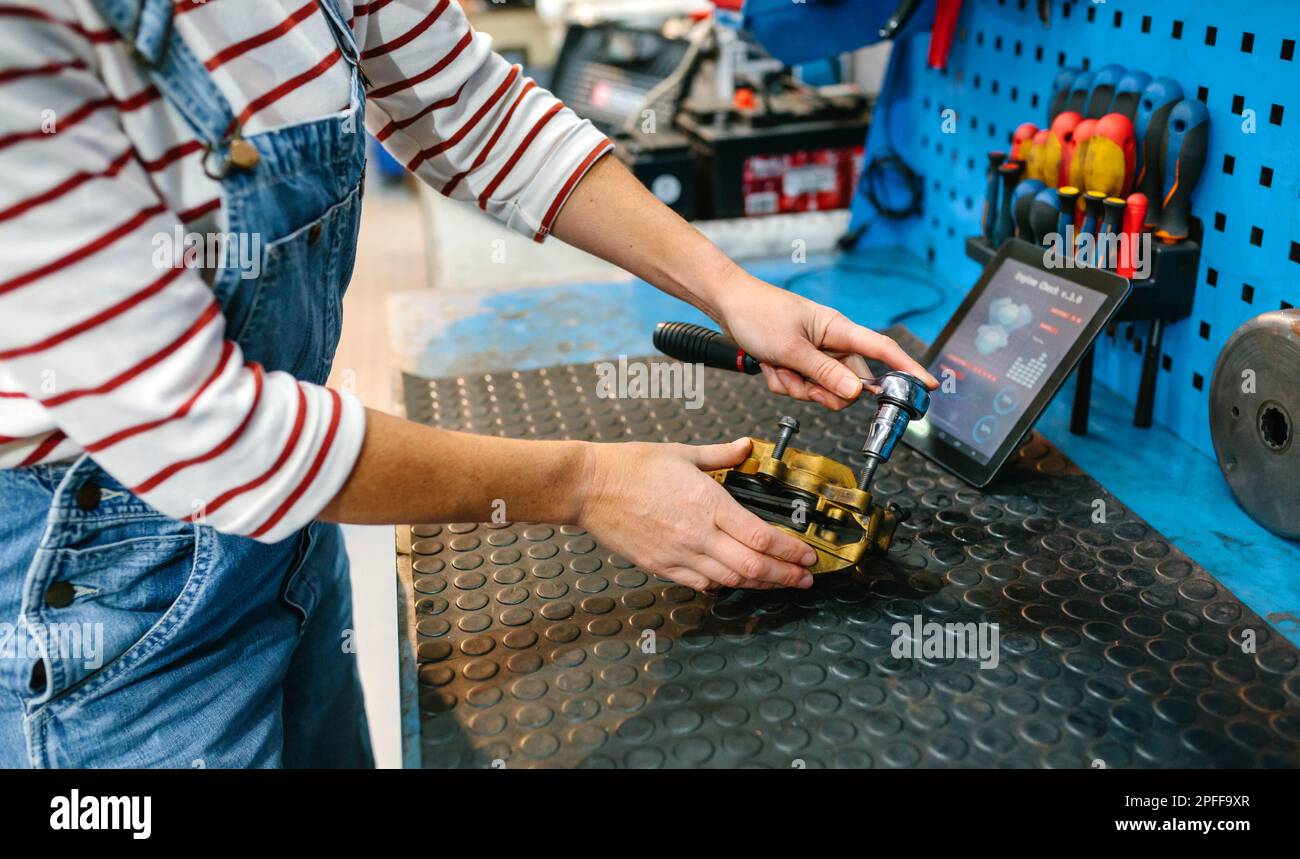 Mechanikerin, die das Bremssattel-Bremssystem über einer Werkbank repariert Stockfoto