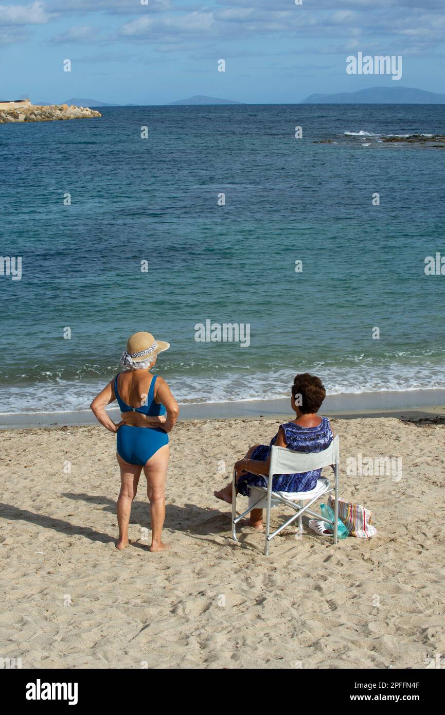 10. Juni 2022: Italien, Sardinien, Sassari, Porto Torres, Zwei Frauen am Strand von Porto Torres vor dem Meer, die sich unterhalten. Stockfoto
