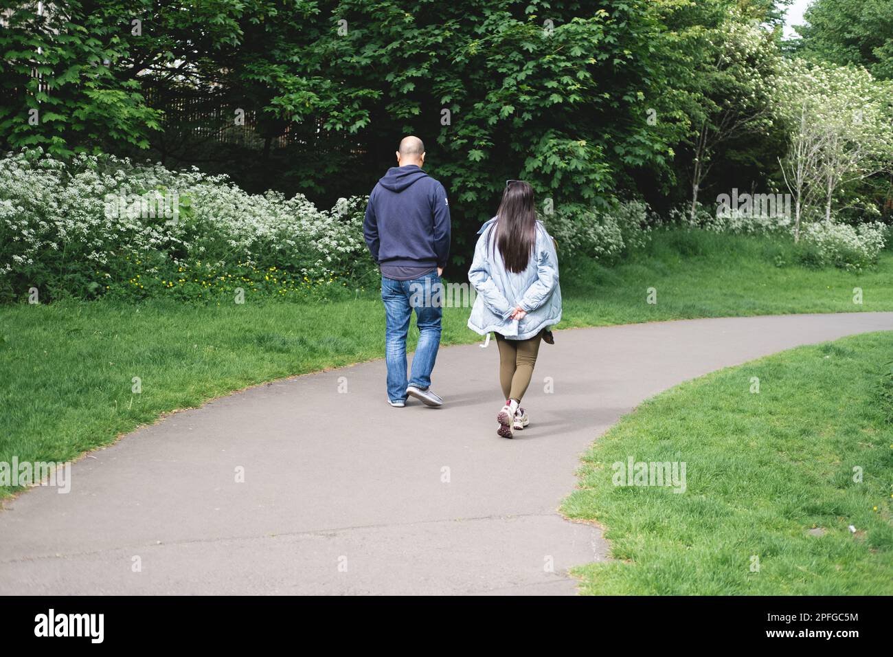 Ein multikulturelles Paar, das im Frühling auf einem Fußweg im Figgate Park in Edinburgh spaziert. Multiethnische Familie. Stockfoto