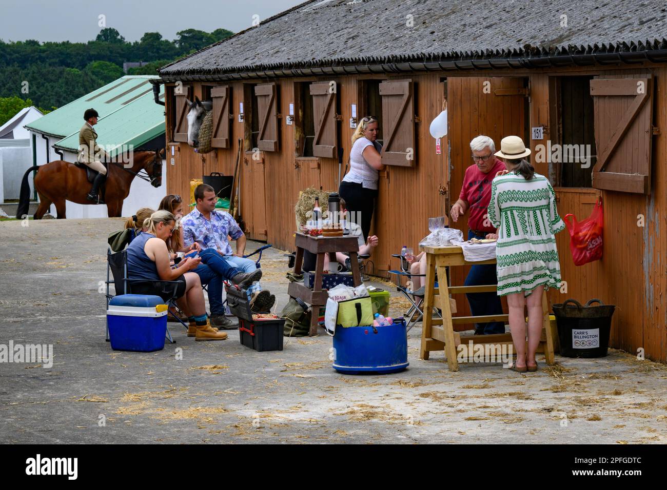 Bräutigame und Pferdebesitzer, die sich in einem Stallhof entspannen, gemeinsam essen und im Freien zu Mittag essen - Great Yorkshire Show, Harrogate, England, Großbritannien. Stockfoto