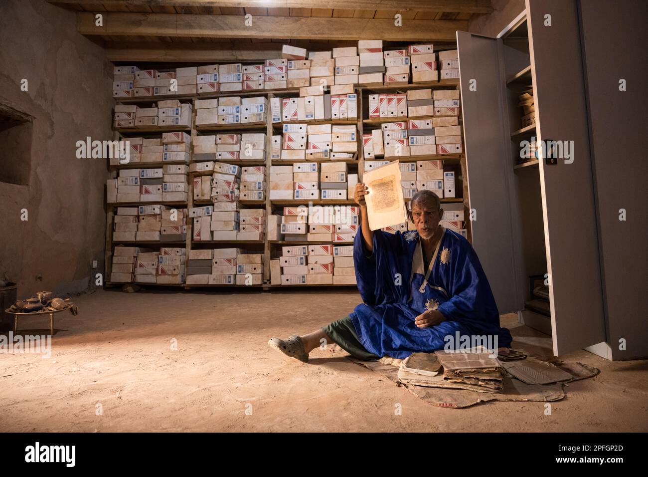 Saif Al Islam von der Ahmed Mahmoud-Bibliothek, die zum UNESCO-Weltkulturerbe gehört und seine Sammlung antiker islamischer Bücher, Chinguetti, Adrar, Mauretanien, zeigt. Stockfoto