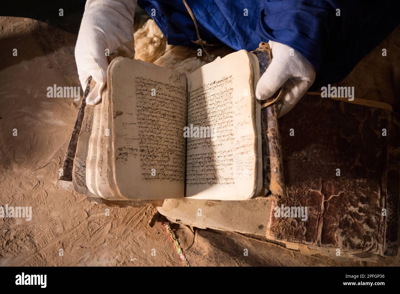 Saif Al Islam von der Ahmed Mahmoud-Bibliothek, die zum UNESCO-Weltkulturerbe gehört und seine Sammlung antiker islamischer Bücher, Chinguetti, Adrar, Mauretanien, zeigt. Stockfoto
